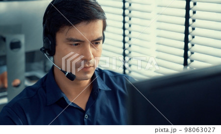 Young competent asian male call center agent working in the office. Young competent asian male call center agent working in the office. 98063027