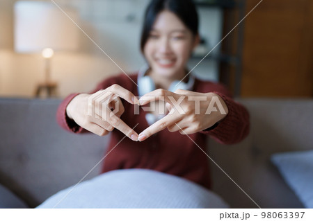 Portrait of beautiful Asian woman showing heart symbol with finger. Portrait of beautiful Asian woman showing heart symbol with finger. 98063397