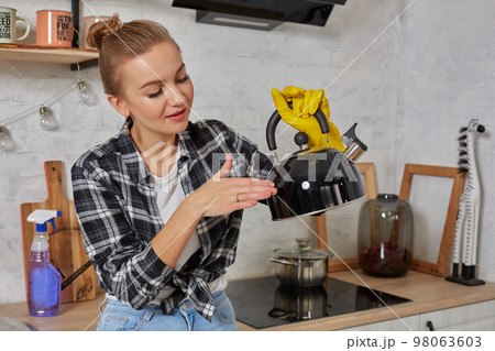 Domestic service and housekeeping concept, happy blonde lady cleaning kitchen kettle. Domestic service and housekeeping concept, happy blonde lady cleaning kitchen kettle. 98063603
