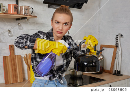 Domestic service and housekeeping concept, happy blonde lady cleaning kitchen kettle. 98063606