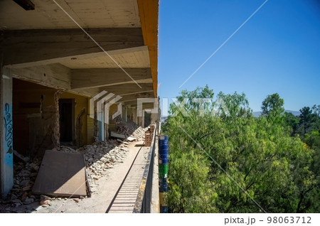 demolition of walls, in a building you can see half of the construction and the trees and sky. concrete walls and roofs demolition of walls, in a building you can see half of the construction and the trees and sky. concrete walls and roofs 98063712