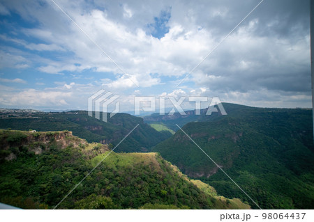 ravine trees and vegetation, view of several mountains at different depths, blue sky and few clouds, mexico 98064437