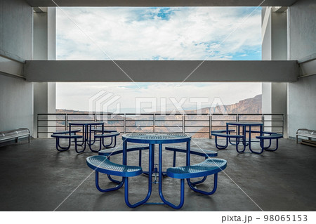 Brutalist concrete architecture, large space overlooking a ravine, blue dining benches. Beam framing the landscape 98065153