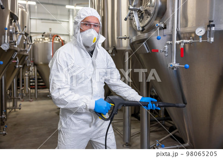 Factory worker disinfecting the beer production equipment Factory worker disinfecting the beer production equipment 98065205
