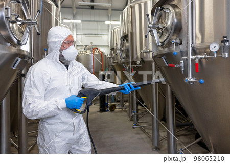 Experienced beer tech cleaning and sanitizing the brewing equipment Experienced beer tech cleaning and sanitizing the brewing equipment 98065210