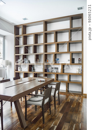 elegant dining room with a bookcase in the background, both the dining table and the natural wood bookcase. 98065231