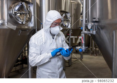 Brewer in protective clothing working at a beer plant Brewer in protective clothing working at a beer plant 98065232