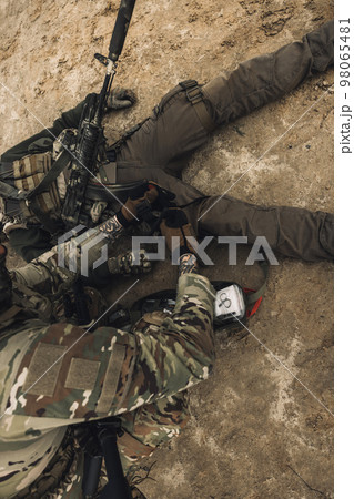 Wounded man lying on a ground, other soldiesr next to him Wounded man lying on a ground, other soldiesr next to him 98065481