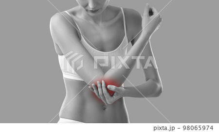 Young woman who is feeling elbow pain due to arm injury is touching painful area 98065974