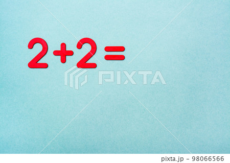 The school task - two plus two - is lined with red plastic figures on a green background. Top View. Copy space The school task - two plus two - is lined with red plastic figures on a green background. Top View. Copy space 98066566