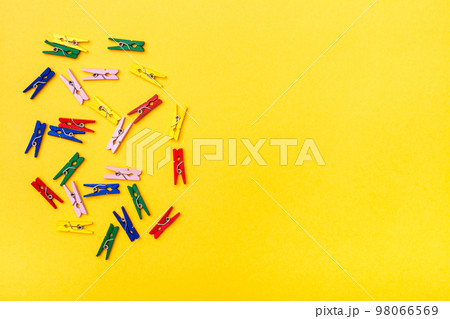 Multicolored wooden clamps lie chaotically on a yellow background. Top View. Copy space Multicolored wooden clamps lie chaotically on a yellow background. Top View. Copy space 98066569
