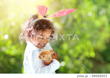 Little curly boy with Easter bunny. 98066603