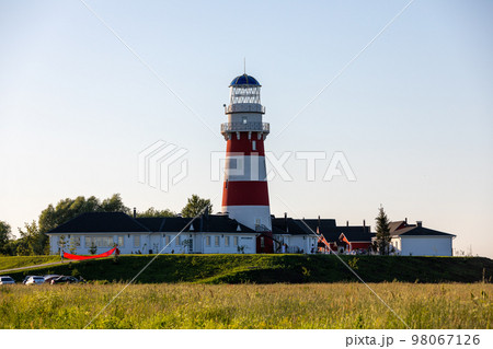 Lighthouse in red and white colors on the seashore, river bank or lake shore. Lighthouse hotel in a fishing village. Travel and tourism concept. Russia, Ryazan region, near the village Shumash. Lighthouse in red and white colors on the seashore, river bank or lake shore. Lighthouse hotel in a fishing village. Travel and tourism concept. Russia, Ryazan region, near the village Shumash. 98067126