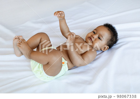 Closeup Shot Of Cute Little Black Baby Lying On Bed At Home Closeup Shot Of Cute Little Black Baby Lying On Bed At Home 98067338