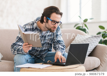 Concentrated serious smart young caucasian man student in glasses looks at laptop, search mistake 98067379
