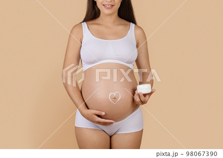 Pregnant woman with heart made of cream painted on her belly Pregnant woman with heart made of cream painted on her belly 98067390