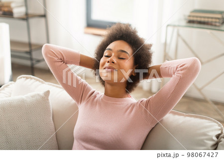 Glad happy young mixed race woman resting on sofa with closed eyes, enjoy peace, silence and free time Glad happy young mixed race woman resting on sofa with closed eyes, enjoy peace, silence and free time 98067427