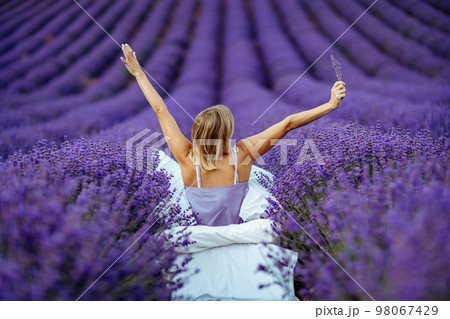 A middle-aged woman sits in a lavender field and enjoys aromatherapy. Aromatherapy concept, lavender oil, photo session in lavender A middle-aged woman sits in a lavender field and enjoys aromatherapy. Aromatherapy concept, lavender oil, photo session in lavender 98067429