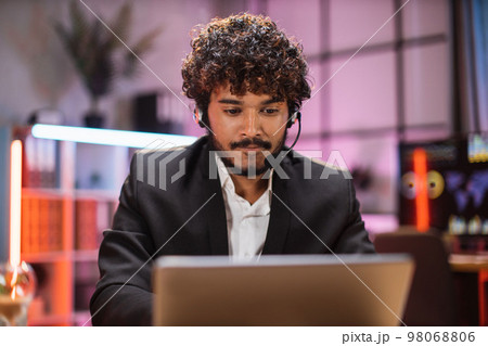 Portrait of confident bearded man in formal wear and headset working at office using laptop. 98068806