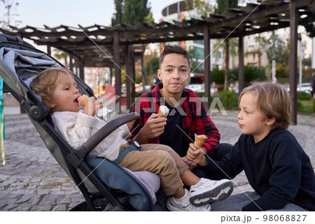 Three brothers boys with ice cream in city park. 98068827