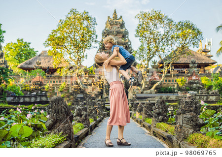 Mom and son travelers in the background of Pura Taman Kemuda Saraswati Temple in Ubud, Bali island, Indonesia Traveling with children concept Mom and son travelers in the background of Pura Taman Kemuda Saraswati Temple in Ubud, Bali island, Indonesia Traveling with children concept 98069765