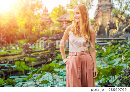 Young woman traveler in the background of Pura Taman Kemuda Saraswati Temple in Ubud, Bali island, Indonesia with sunlight Young woman traveler in the background of Pura Taman Kemuda Saraswati Temple in Ubud, Bali island, Indonesia with sunlight 98069766