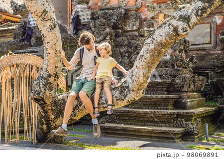 Dad and son travelers in the background of Pura Taman Kemuda Saraswati Temple in Ubud, Bali island, Indonesia BANNER, long format Traveling with children concept Dad and son travelers in the background of Pura Taman Kemuda Saraswati Temple in Ubud, Bali island, Indonesia BANNER, long format Traveling with children concept 98069891