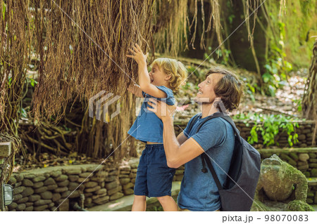 Dad and son travelers discovering Ubud forest in Monkey forest, Bali Indonesia. Traveling with children concept 98070083
