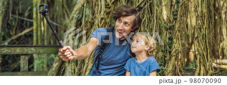 Dad and son travelers discovering Ubud forest in Monkey forest, Bali Indonesia. Traveling with children concept. Videoblog, Selfie. BANNER, long format Dad and son travelers discovering Ubud forest in Monkey forest, Bali Indonesia. Traveling with children concept. Videoblog, Selfie. BANNER, long format 98070090