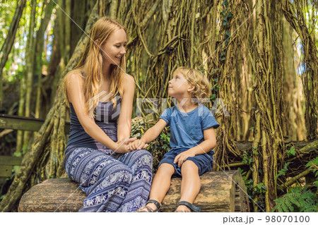 Mom and son travelers discovering Ubud forest in Monkey forest, Bali Indonesia. Traveling with children concept Mom and son travelers discovering Ubud forest in Monkey forest, Bali Indonesia. Traveling with children concept 98070100