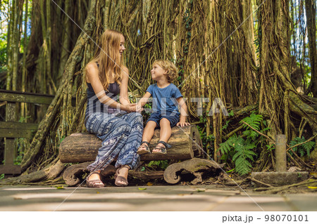 Mom and son travelers discovering Ubud forest in Monkey forest, Bali Indonesia. Traveling with children concept 98070101