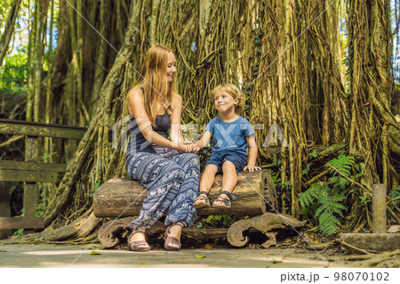 Mom and son travelers discovering Ubud forest in Monkey forest, Bali Indonesia. Traveling with children concept 98070102