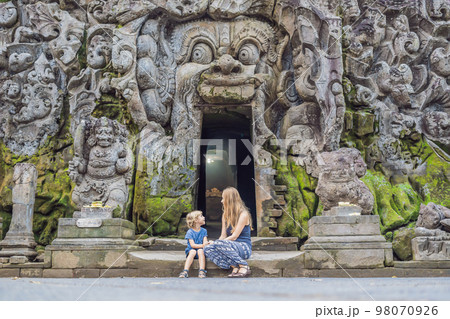 Mom and son are tourists in Old Hindu temple of Goa Gajah near Ubud on the island of Bali, Indonesia. Travel in Bali with children concept Mom and son are tourists in Old Hindu temple of Goa Gajah near Ubud on the island of Bali, Indonesia. Travel in Bali with children concept 98070926