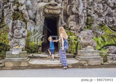 Mom and son are tourists in Old Hindu temple of Goa Gajah near Ubud on the island of Bali, Indonesia. Travel in Bali with children concept Mom and son are tourists in Old Hindu temple of Goa Gajah near Ubud on the island of Bali, Indonesia. Travel in Bali with children concept 98070943