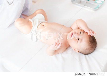 診察台の上で体調が悪そうな赤ちゃん 診察台の上で体調が悪そうな赤ちゃん 98071390