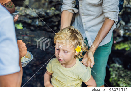 Boy is a tourist in Bali. The ritual of ablution with holy water and on her forehead prikleeli rice and put the flower ear Boy is a tourist in Bali. The ritual of ablution with holy water and on her forehead prikleeli rice and put the flower ear 98071515
