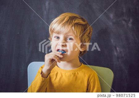 Three-year old boy shows myofunctional trainer. Helps equalize the growing teeth and correct bite, develop mouth breathing habit. Corrects the position of the tongue 98071525