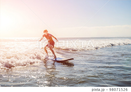 Young man, beginner Surfer learns to surf on a sea foam on the Bali island 98071526