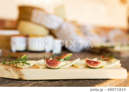 Various types of yellow cheese and fruits on cutting board served on rustic wooden table. French tasting party or holiday scenery 98071924