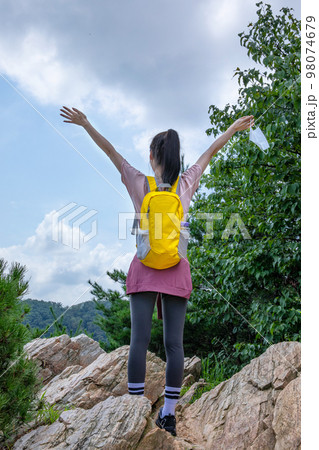 korean young women hiking and plogging_looking back holding a mask 98074679