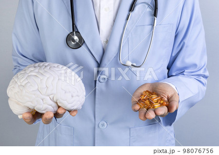 brain health and dementia series_docotr holding brain miniature and omega 3 98076756