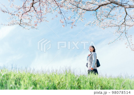 桜の咲いた河川敷を通学する女子高生 98078514