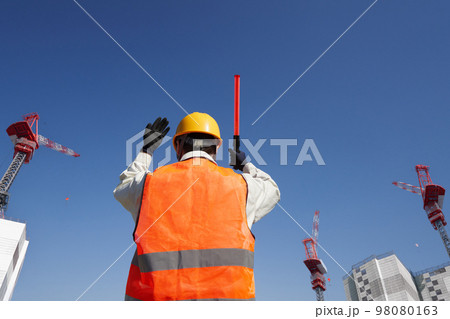 工事現場で交通誘導をする安全ベスト着用の男性の後姿 98080163