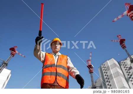 工事現場で交通誘導をする安全ベスト着用の男性 工事現場で交通誘導をする安全ベスト着用の男性 98080165