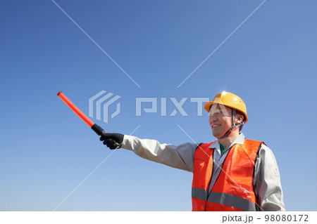 青空のもと交通誘導をする安全ベスト着用の男性 青空のもと交通誘導をする安全ベスト着用の男性 98080172
