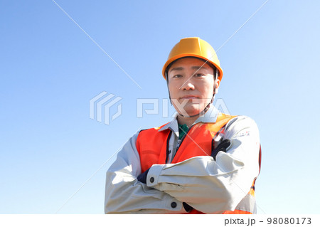 青空のもと腕組みをする安全ベスト着用の男性 青空のもと腕組みをする安全ベスト着用の男性 98080173