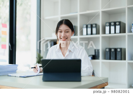 Portrait of a thoughtful Asian businesswoman looking at financial statements and making marketing plans using a computer on her desk. Portrait of a thoughtful Asian businesswoman looking at financial statements and making marketing plans using a computer on her desk. 98082001