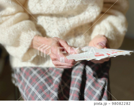 年賀状を広げて見る高齢女性の手 98082282