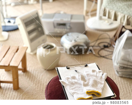 たくさんの電化製品などの前に置いたクリップボードと軍手 98083565