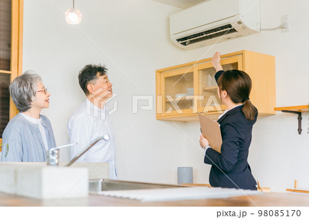 住宅展示場・モデルルーム・ハウスメーカーで高齢者夫婦に説明するビジネスウーマン（エアコン・空調） 98085170